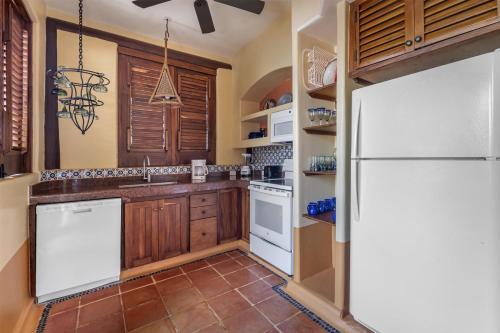 a kitchen with wooden cabinets and a white refrigerator at Hilton Grand Vacations Club Zihuatanejo in Zihuatanejo