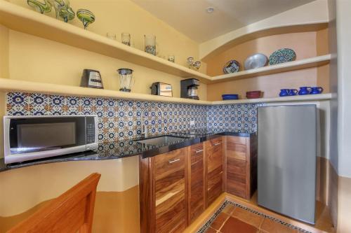 a kitchen with wooden cabinets and a stainless steel refrigerator at Hilton Grand Vacations Club Zihuatanejo in Zihuatanejo