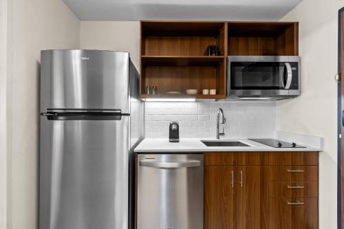 a kitchen with a stainless steel refrigerator and a microwave at Everhome Suites Chandler Phoenix Fashion Center in Chandler