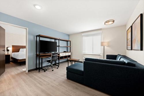 a living room with a couch and a desk with a television at Everhome Suites Huntsville - Research Park in Huntsville