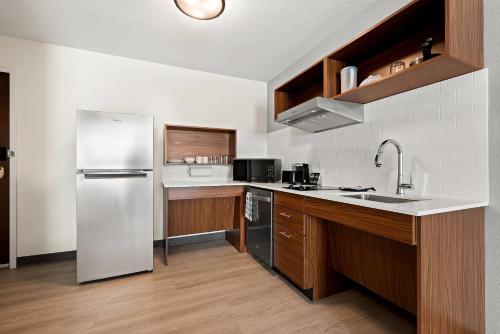 a kitchen with a stainless steel refrigerator and wooden cabinets at Everhome Suites Huntsville - Research Park in Huntsville