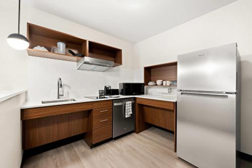 a kitchen with a stainless steel refrigerator and wooden cabinets at Everhome Suites Huntsville - Research Park in Huntsville