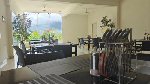 Golden Hill Resort في تشكماغالور: مطعم بطاولات وكراسي ونافذة كبيرة