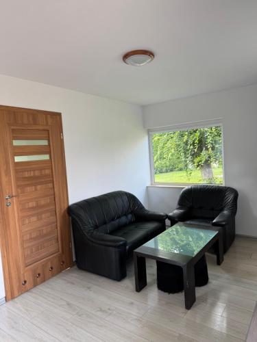 a living room with a black leather couch and a table at Ranczo Ryki in Nowy Dwór Gdański