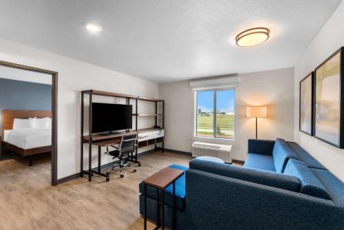 a living room with a couch and a tv and a bed at Everhome Suites Bastrop in Bastrop