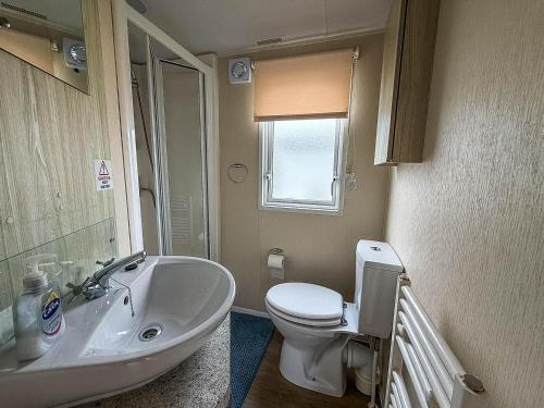 a bathroom with a white toilet and a sink at Lovely 6 Berth Caravan At Seawick Holiday Park In Essex Ref 27008S in Clacton-on-Sea