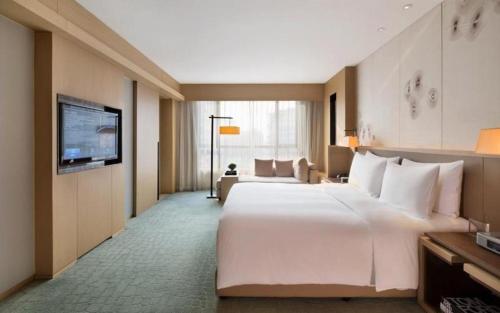Habitación de hotel con cama blanca grande y TV en The East Hotel Hangzhou, en Hangzhou