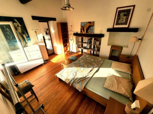 a bedroom with a large bed and a wooden floor at Charming brickyard cottage near a lock in Ayguesvives