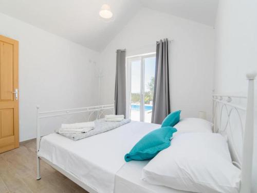 ein weißes Bett mit blauen Kissen im Schlafzimmer in der Unterkunft Holiday Home My Summer House - Two-Bedroom Holiday Home with Private Pool and Terrace - ST in Supetar