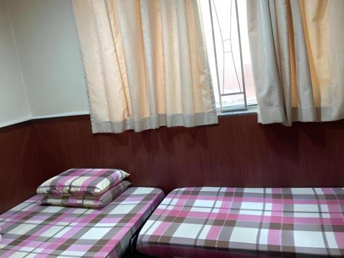 two beds sitting in a room with a window at New Mong Kok Guest House in Hong Kong