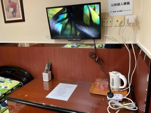 a desk with a television and a remote control on it at New Mong Kok Guest House in Hong Kong