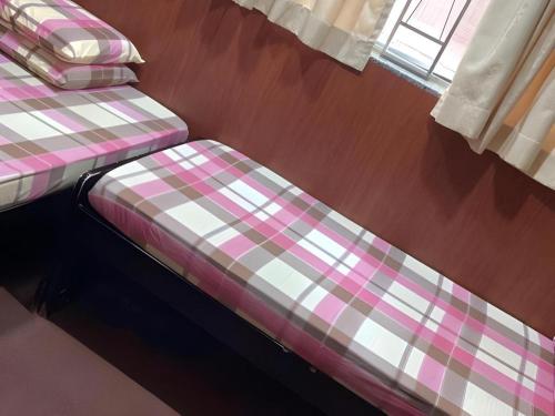 two beds in a room with a checkered blanket at New Mong Kok Guest House in Hong Kong