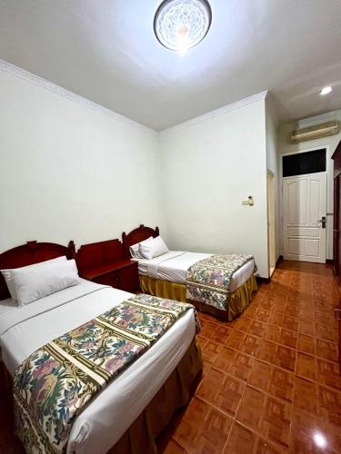 a hotel room with two beds and a door at Soeltan Luxe Hotel Lampung in Bandar Lampung