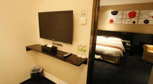 a hotel room with a television and a bed at Noble Park Hotel in Hong Kong
