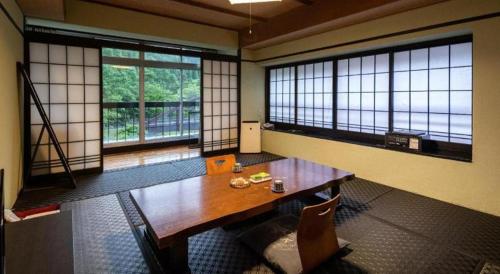 a room with a wooden table and two large windows at Hotel Myoken Tanaka Kaikan in Kirishima