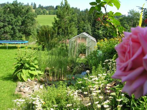 a garden with a greenhouse in the background at Ferienwohnungen Bergblick in Immenstadt im Allgäu