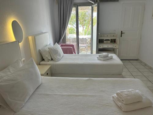 a hotel room with two beds and a balcony at Paolas Sunset in Agios Stefanos