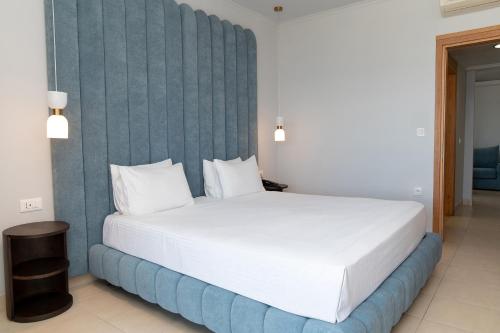 a bedroom with a white bed with a blue wall at Grand Blue Beach Hotel in Kardamaina