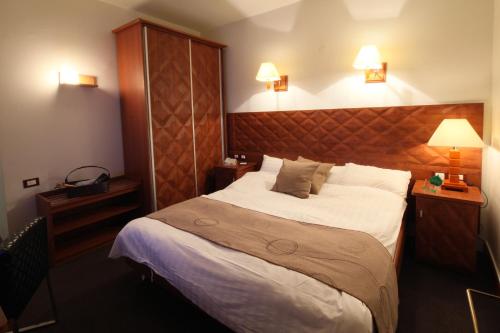 a bedroom with a large bed and two lights on at Plasma Hotel Tripoli in Tripoli