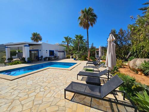 a swimming pool with two chairs and an umbrella at Villa en Sa Caleta - CAN BLAU IBIZA in Ibiza Town