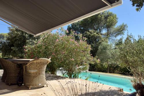 un patio avec une table et des chaises à côté d'une piscine dans l'établissement Les Lauriers Roses air-conditioned villa with garden and swimming pool, à Saumane-de-Vaucluse