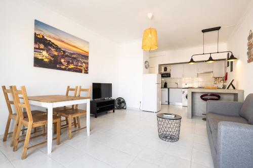 a living room with a table and a kitchen at Hoso Apartments T1 in Costa da Caparica