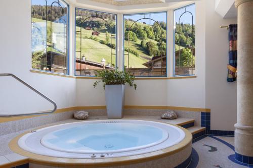 a large tub in a room with windows at Hotel Platzer Superior in Gerlos