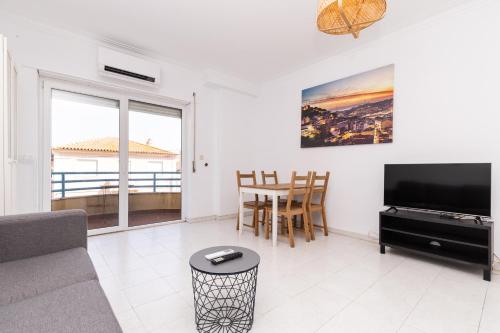 a living room with a couch and a tv and a table at Hoso Apartments T1 in Costa da Caparica