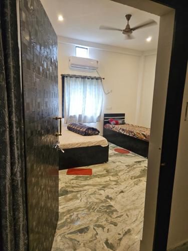 a room with two beds and a window at Pandit Devki Nandan Dharamsala & Guest House in Deoghar