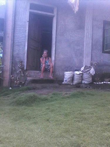 a woman sitting on the porch of a house at Belmoro Transient House in Bacacay