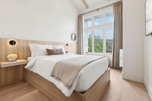 a white bedroom with a large bed and a window at Casa Riviera - Boutique Apartments in Downtown Santa Barbara in Santa Barbara