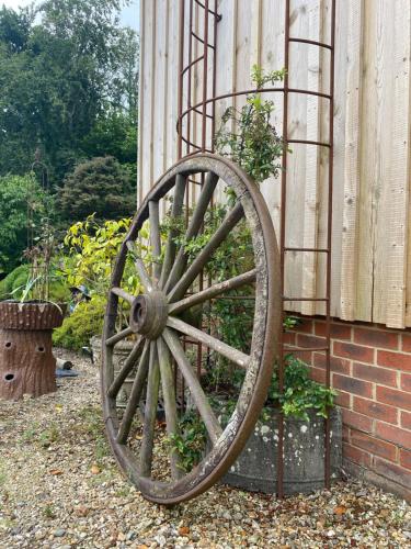 a wooden wagon wheel sitting next to a brick wall at 2 Bed Countryside Retreat in Dorset Includes a private Hot Tub and cosy wood burner in Horton