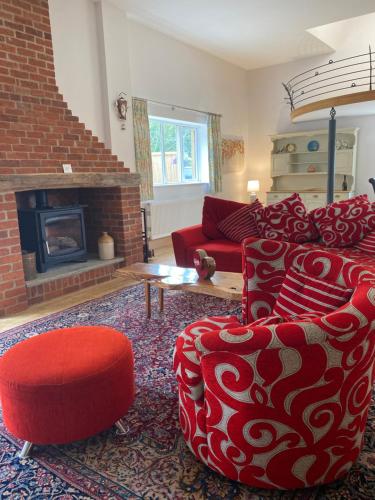 a living room with red furniture and a fireplace at 2 Bed Countryside Retreat in Dorset Includes a private Hot Tub and cosy wood burner in Horton