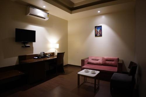 a hotel room with a red chair and a desk at Hotel Sadanand Regency - Newly Renovated in Pune