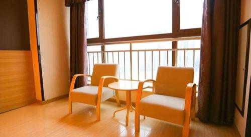 two chairs and a table in a room with a window at 7 Days Premium Xi'an Dayan Tower Xiaozhai Metro Station in Xi'an