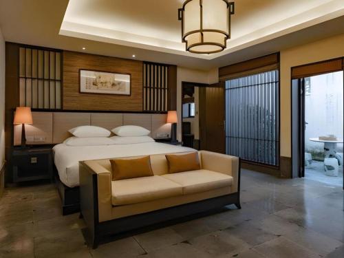 a bedroom with a bed and a couch and a chandelier at Hotel Dayu Kaiyuan in Shaoxing