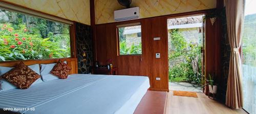 a bedroom with a bed in a room with windows at Hang Mua Eco Garden in Xuân Sơn