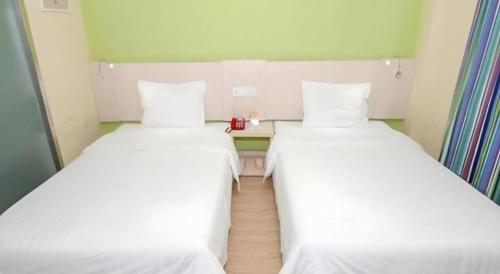 two beds in a small room with white sheets at 7 Days Inn Changchun Zhengyang Street Changchun Park Branch in Changchun