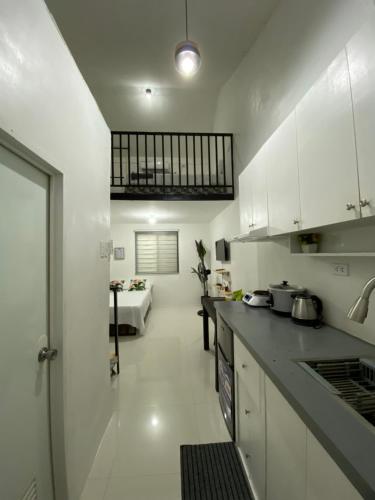 a kitchen with white cabinets and a living room at JNJ Apartelle in Tacurong