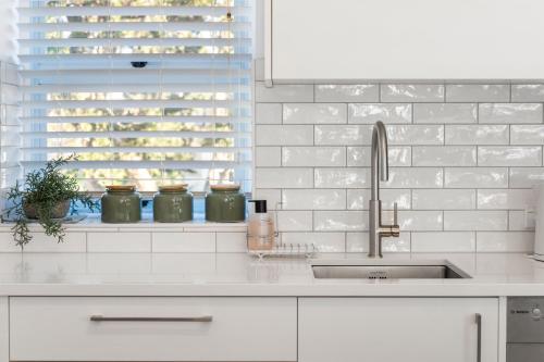 a white kitchen with a sink and a window at Sea Breeze - Orewa Oceanside Apartments in Orewa