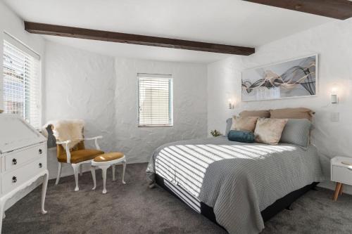 a bedroom with a bed and a desk and a chair at Sea Breeze - Orewa Oceanside Apartments in Orewa