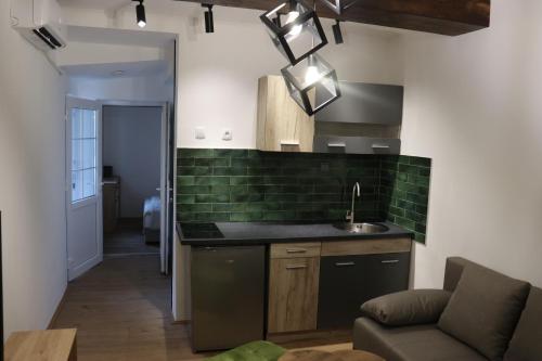 Una cocina con fregadero y azulejos verdes en la pared. en Central House Niš, en Niš