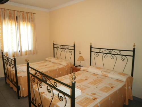 a bedroom with two beds and a window at Hostal Miraflor de las Cadenas in Cuacos de Yuste