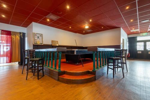 a bar in a room with a stage and stools at Injoy Classic Hotel Halmstad in Halmstad