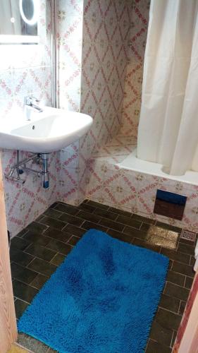 ein Badezimmer mit Waschbecken und einem blauen Teppich auf dem Boden in der Unterkunft Seeblick Zimmer in Seewalchen
