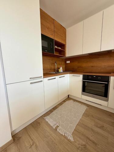 a kitchen with white cabinets and a rug on the floor at Allvia apartment in Trnava