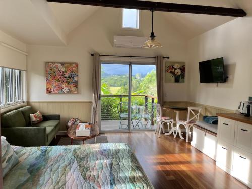 a bedroom with a bed and a living room with a balcony at Gridley Homestead B&B in Eumundi