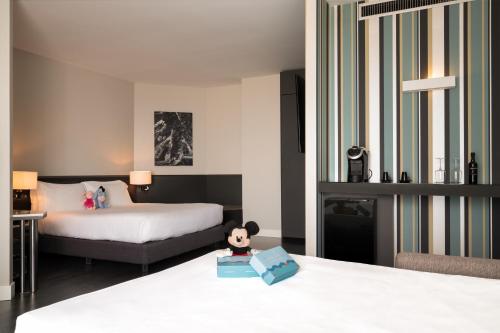 a hotel room with two beds and a doll sitting on a box at The Nicolaus Hotel in Bari