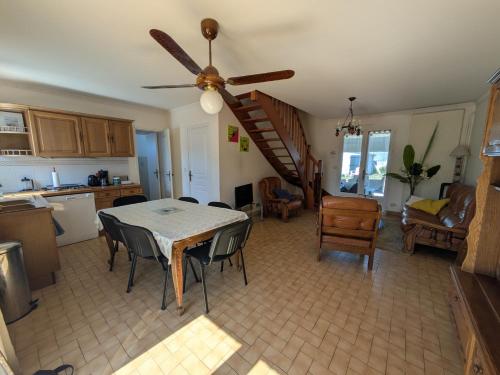 eine Küche und ein Esszimmer mit einem Tisch und einem Deckenventilator in der Unterkunft Maison de vacances 400 m de la plage et du port de la Turballe in La Turballe