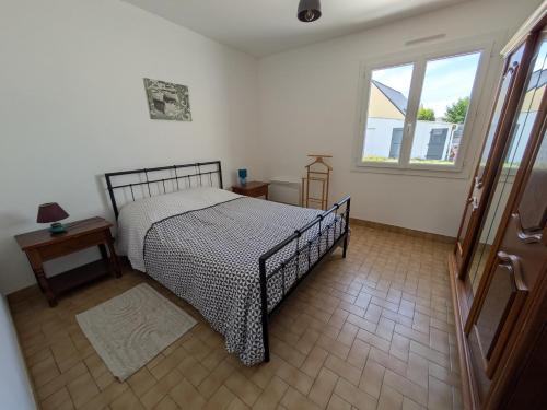 ein Schlafzimmer mit einem Bett und einem Fenster in der Unterkunft Maison de vacances 400 m de la plage et du port de la Turballe in La Turballe